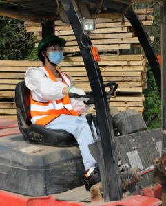 Safety-first: Worker operating a forklift with a reflective vest to meet safety standards.