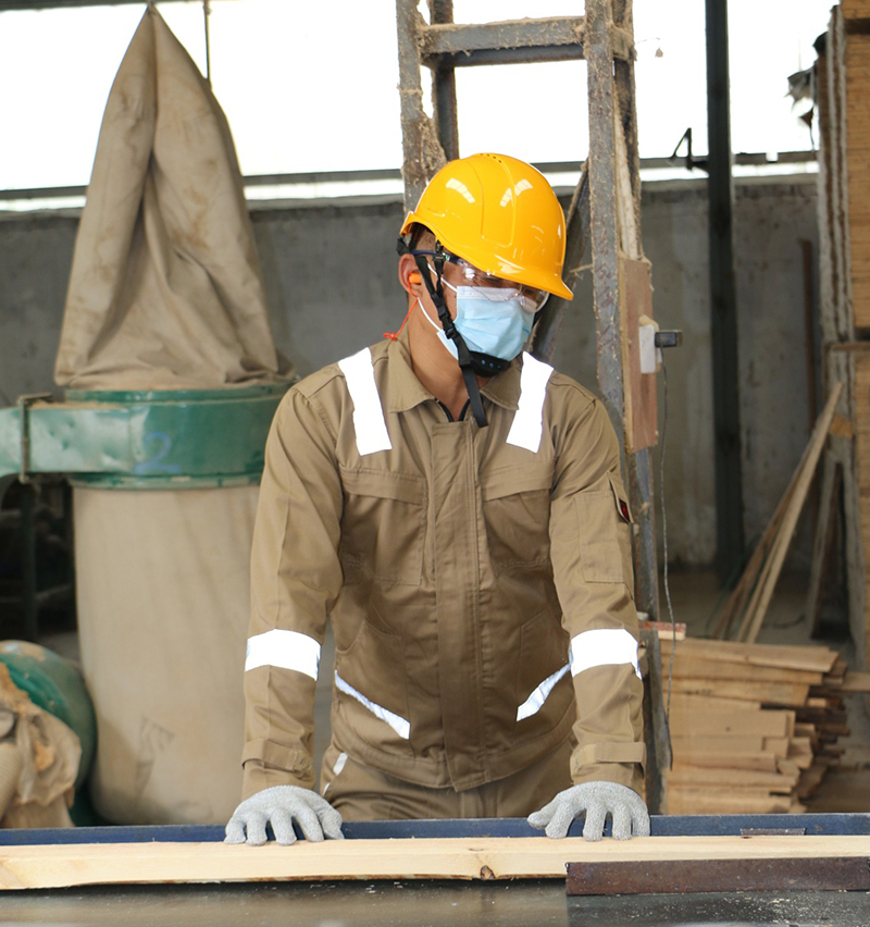 Worker in EN 13688-compliant reflective fire-resistant workwear performing wood processing, ensuring safety and visibility.